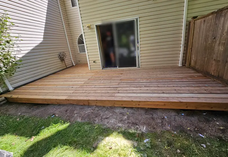 The finished ground-level cedar deck across the back of the house, next to a cedar fence