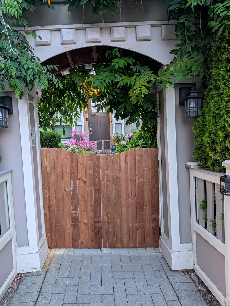 The same arbor entry after, with a new stained cedar double gate in place of the painted one