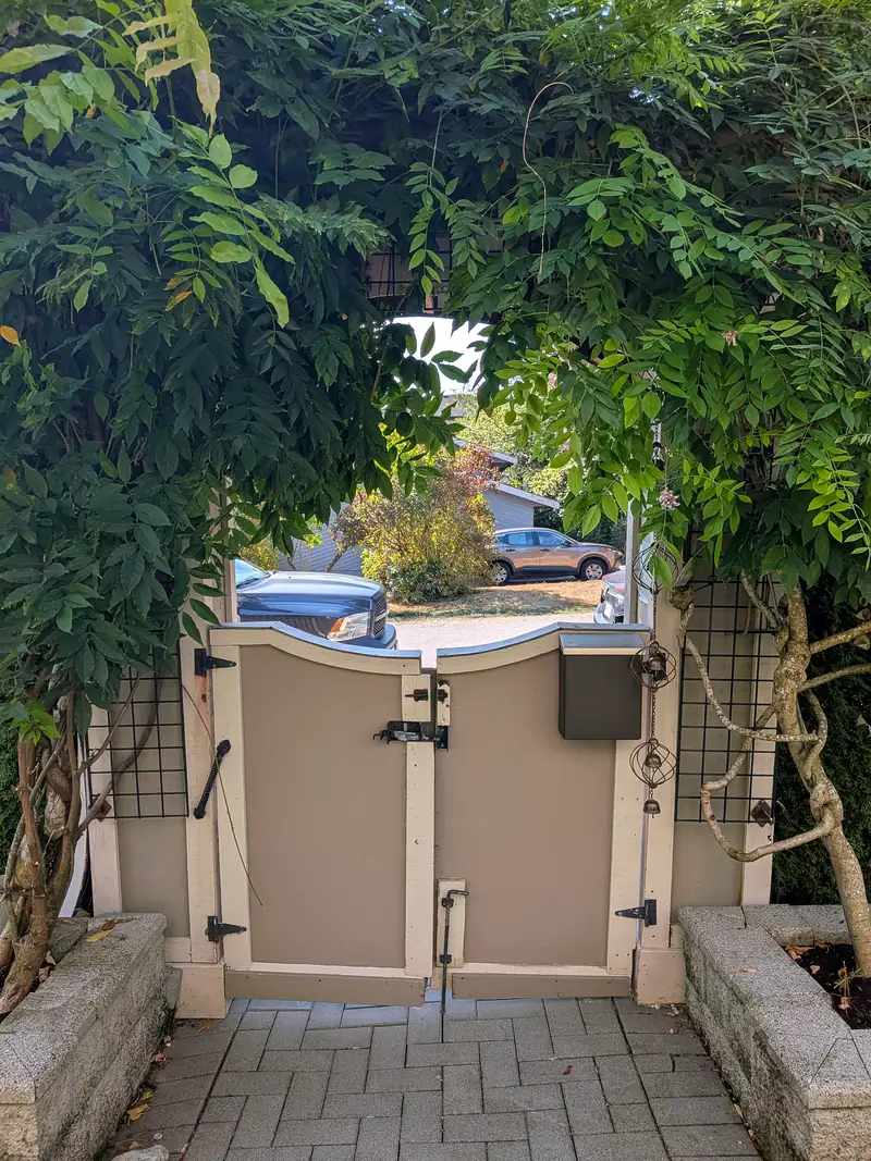 The same gate from inside the yard before, painted panels with older latch hardware between raised planters