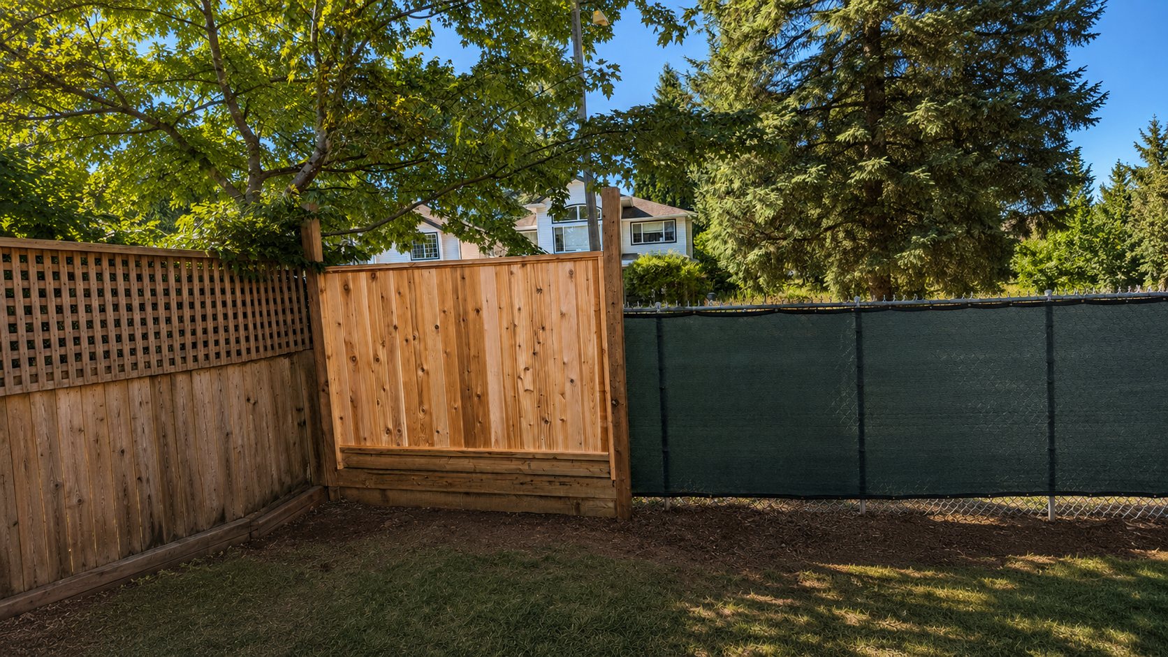 The first new board-on-board cedar panel and gate post set next to the old green privacy fence
