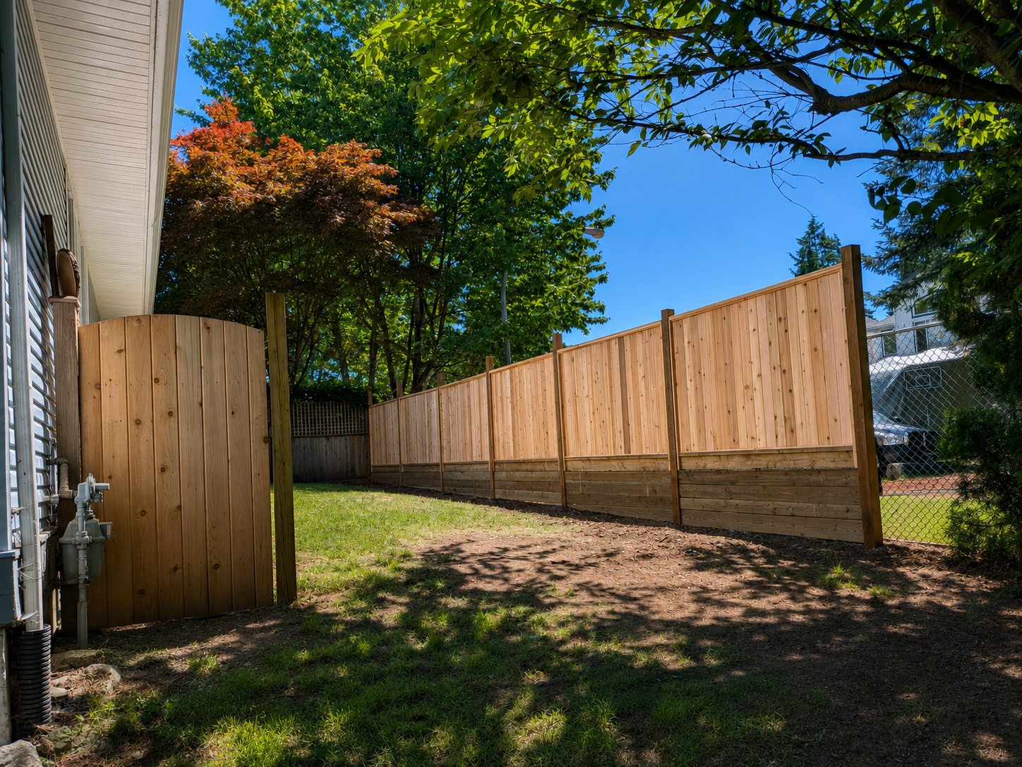 The finished western red cedar fence run and matched arched gate along a Peninsula backyard